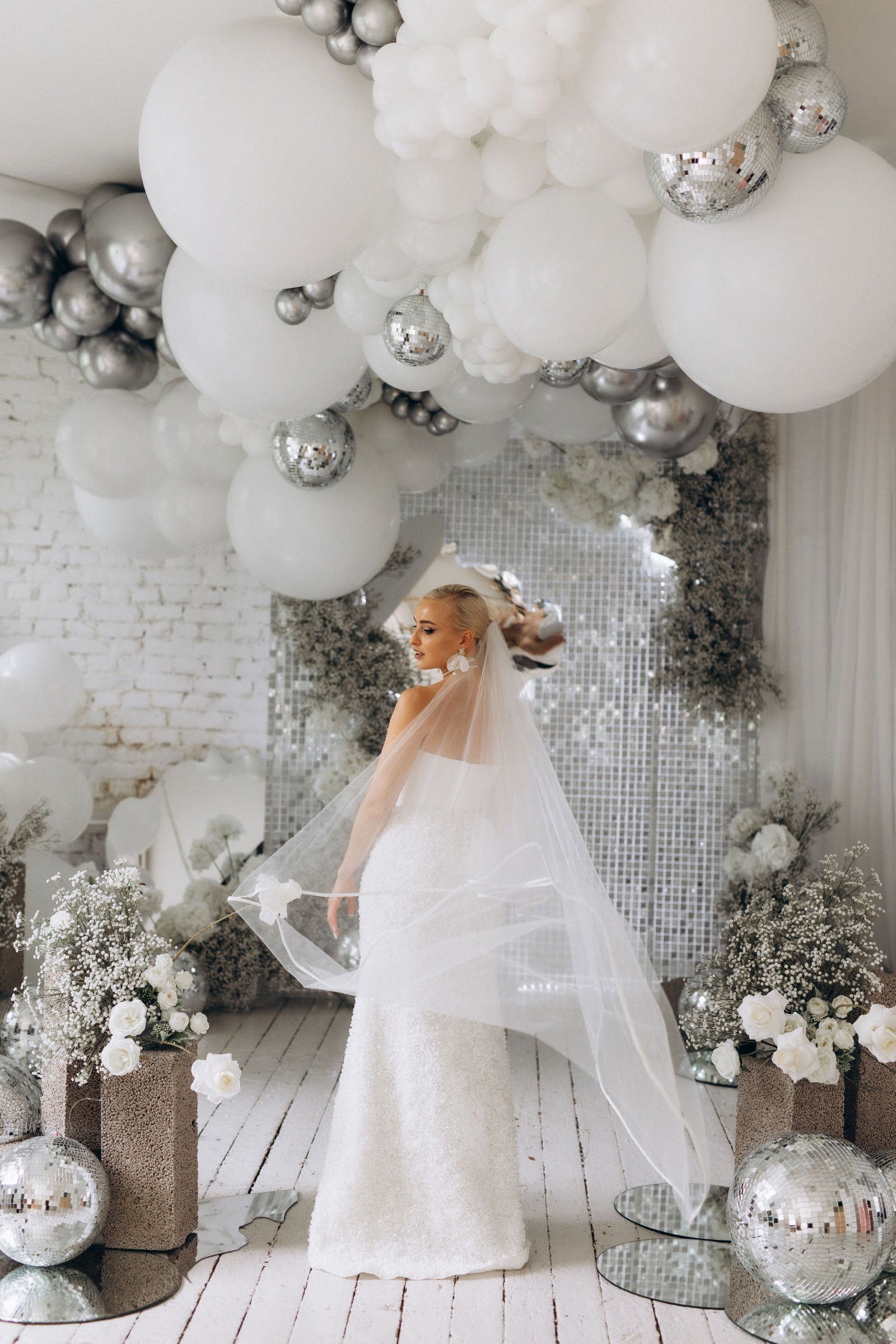 White balloon garland with disco balls over a sequin wall backdrop
