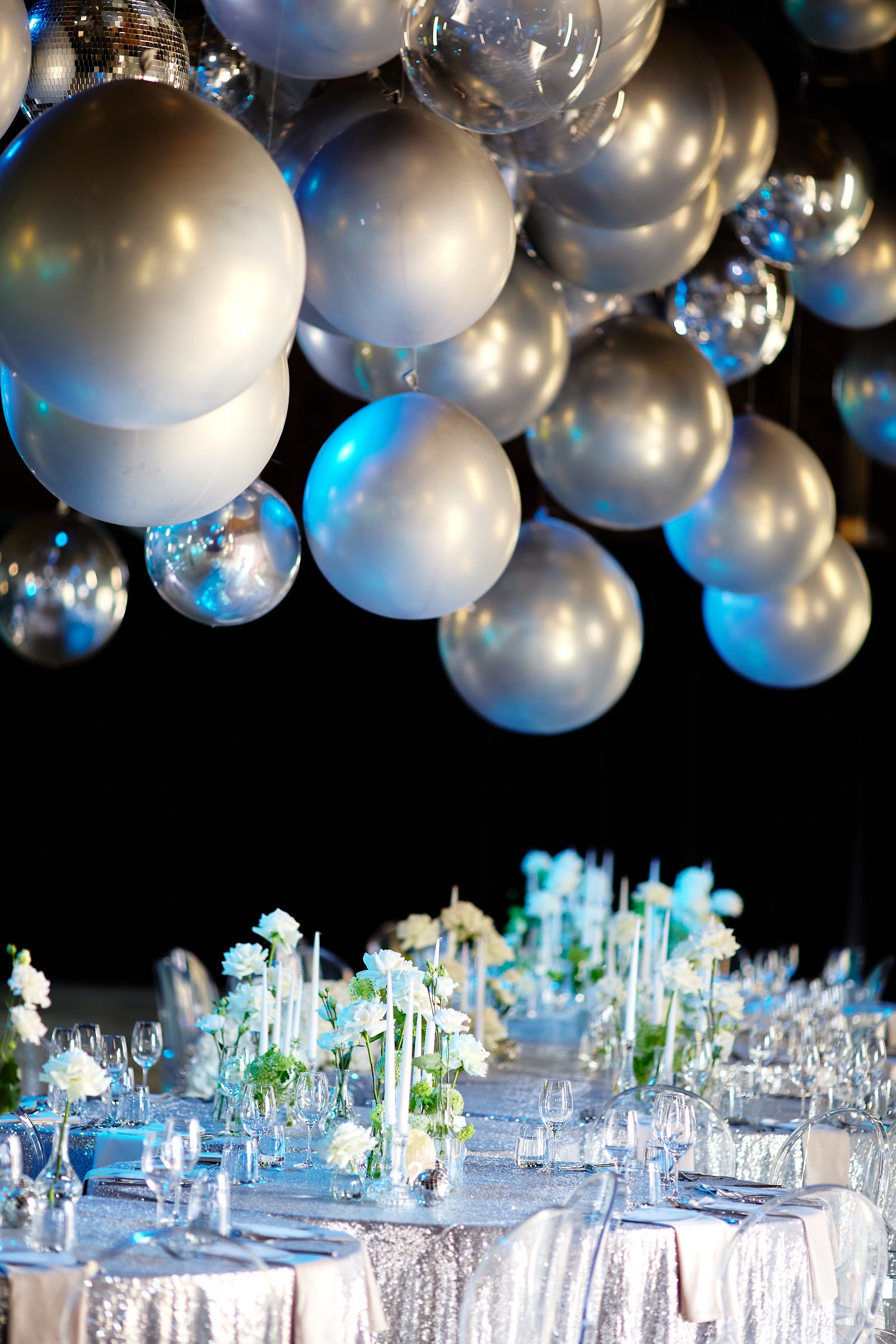 Metallic balloons suspended as ceiling decor in a dark venue