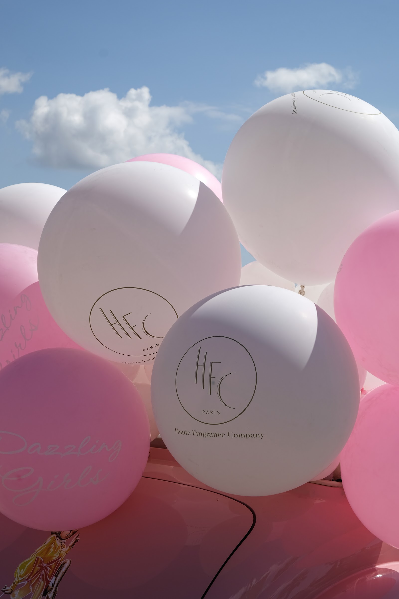 Pink and white helium balloons floating against the sky
