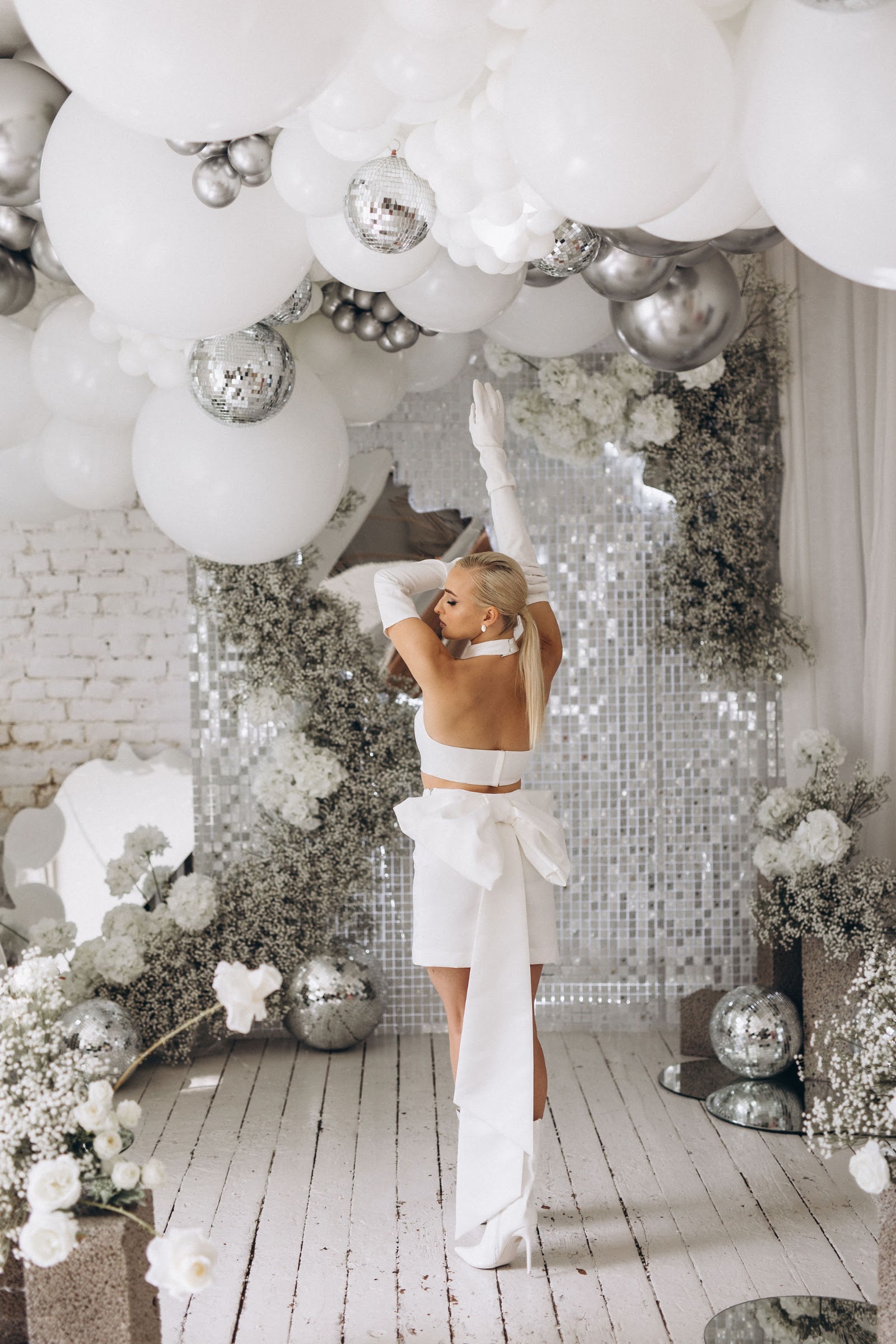 White balloon installation over a mirror sequin wall